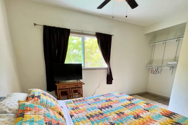 a bedroom with a bed and a flat tv screen on dresser
