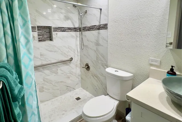 a white toilet sitting next to a bathroom sink and tub