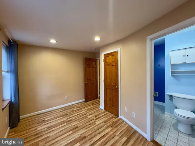 a view of a hallway with wooden floor and a bathroom