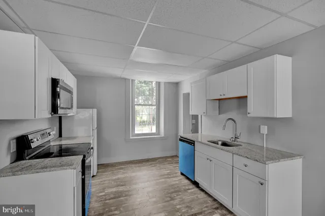a kitchen with stainless steel appliances white cabinets and a stove top oven