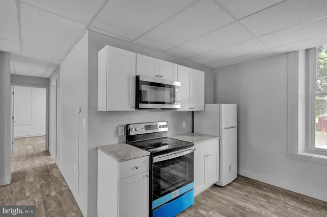a kitchen with stainless steel appliances granite countertop white cabinets sink and window