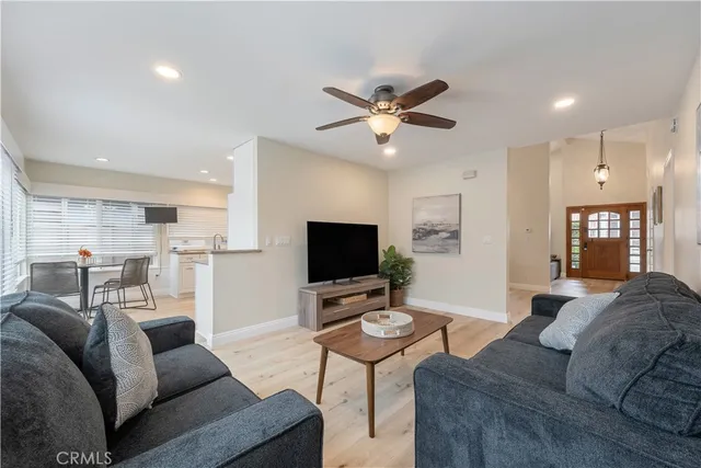 a living room with furniture a flat screen tv and kitchen view