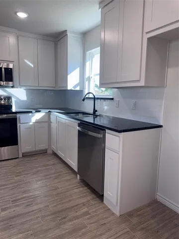 a kitchen with granite countertop white cabinets and a sink