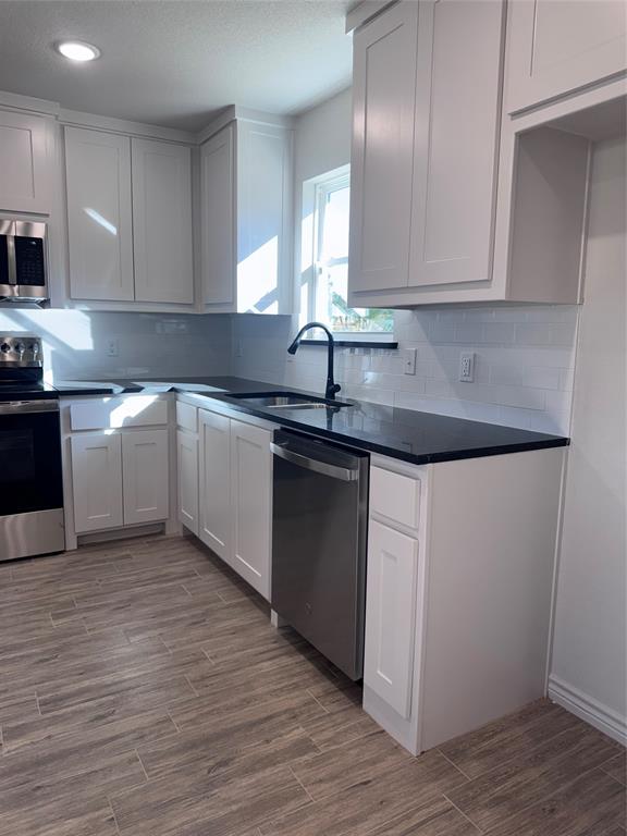 1013 East Bradshaw Road Springtown, TX 76082 - Photo 2 of 6 a kitchen with granite countertop white cabinets and a sink