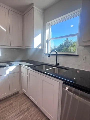 a kitchen with granite countertop white cabinets and sink