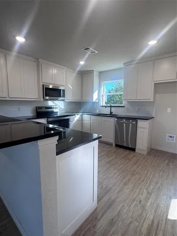 a kitchen with stainless steel appliances a sink a stove a refrigerator and cabinets