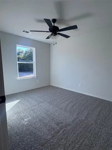 an empty room with a ceiling fan and window
