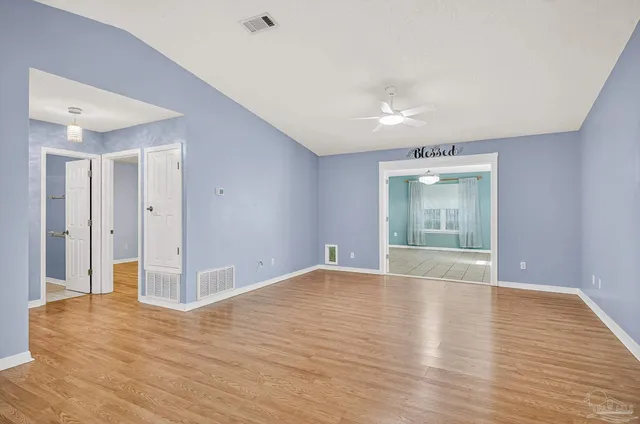 a view of an empty room with wooden floor and windows