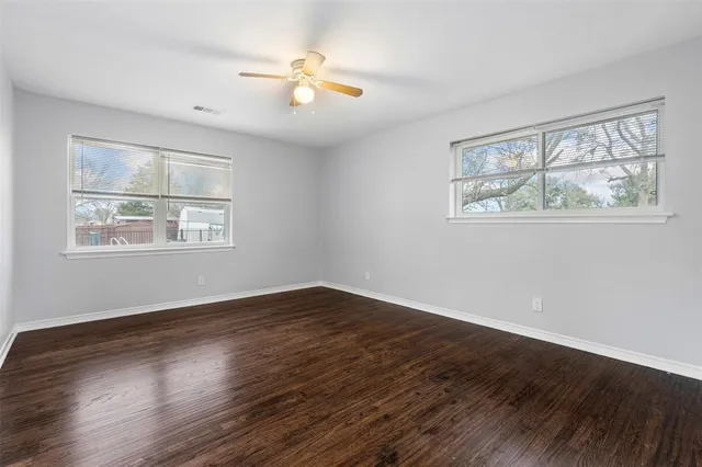 a view of an empty room with wooden floor and window