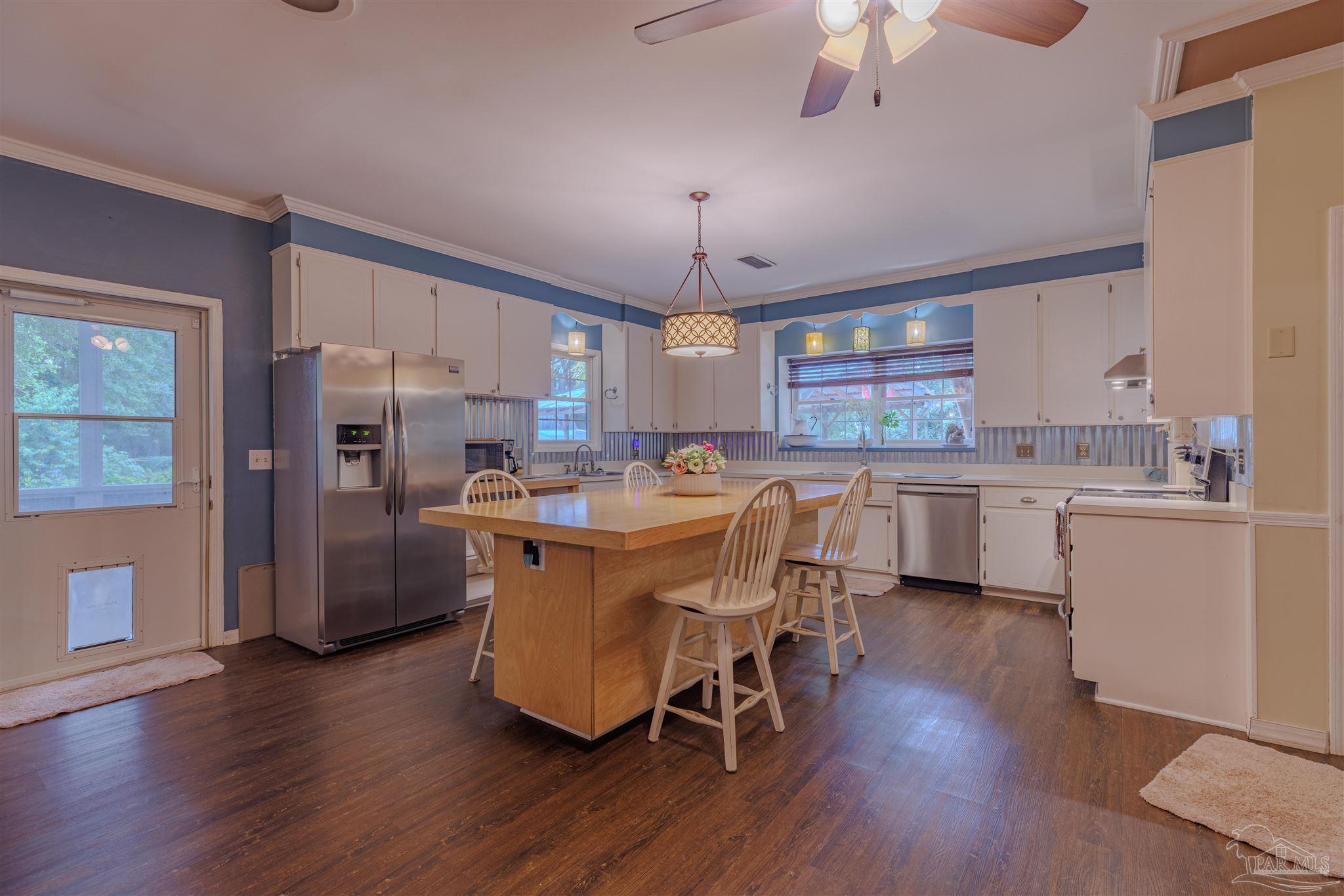5049 Guernsey Road Pace, FL 32571 - Photo 21 of 61 a kitchen with stainless steel appliances a dining table chairs a refrigerator and cabinets