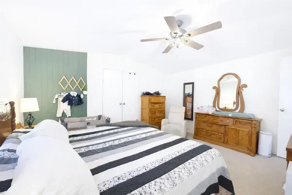 a bedroom with a bed and dresser with wooden floor