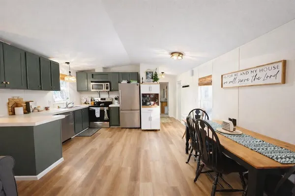 a kitchen with granite countertop a refrigerator a stove a sink dishwasher and white cabinets with wooden floor