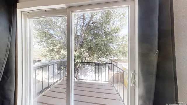 a view of a room with a large window and wooden floor