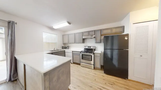 a kitchen with a refrigerator a sink dishwasher and a stove with wooden floor