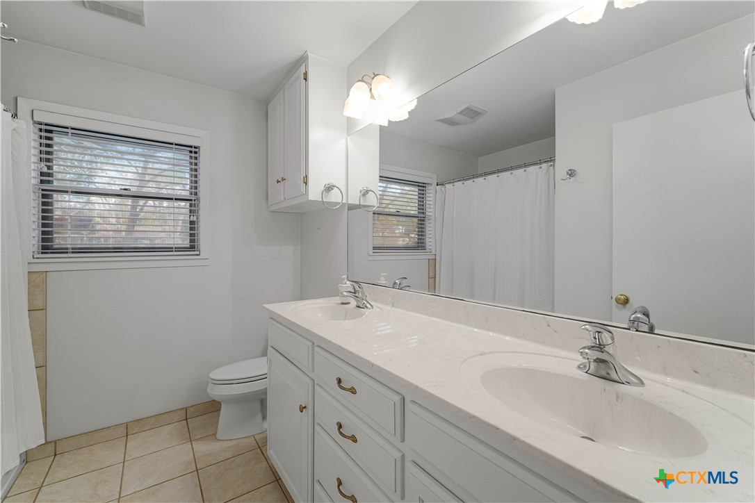 406 Blyth Road Victoria, TX 77904 - Photo 22 of 32 a bathroom with a granite countertop sink a toilet and a mirror