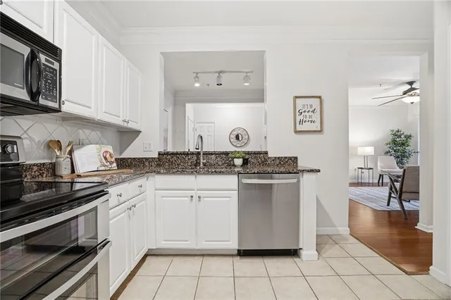 a kitchen with stainless steel appliances granite countertop a stove a sink and white cabinets