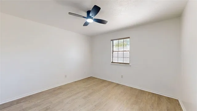 an empty room with a window and a fan