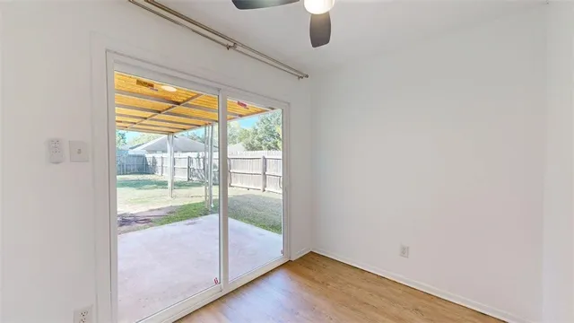 a view of a room with a ceiling fan and wooden floor