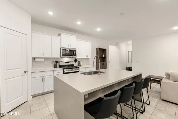 a kitchen with a sink a stove a refrigerator and white cabinets
