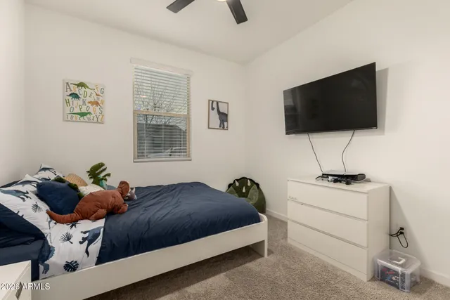a bedroom with a bed a flat screen tv and a window