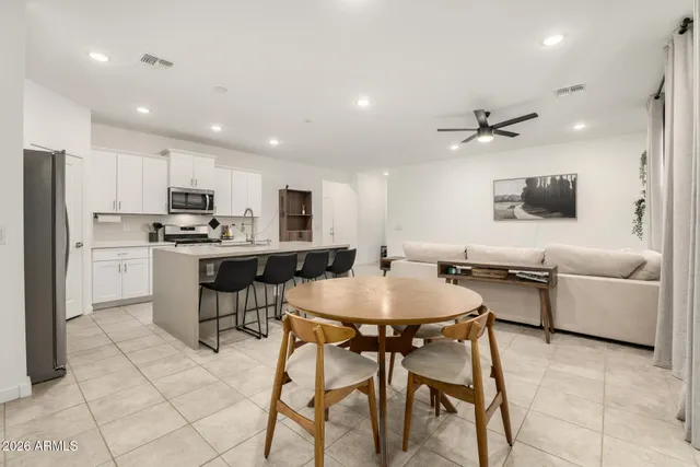 a living room with stainless steel appliances kitchen island granite countertop a dining table chairs and a refrigerator