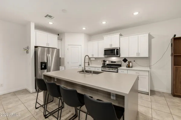 a kitchen with a refrigerator a stove a microwave oven with a dining table and chairs