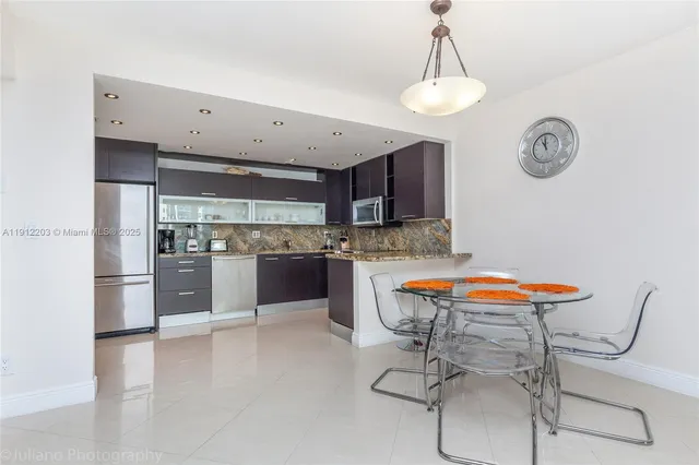 a kitchen with stainless steel appliances granite countertop a sink a stove a refrigerator and island with wooden floor