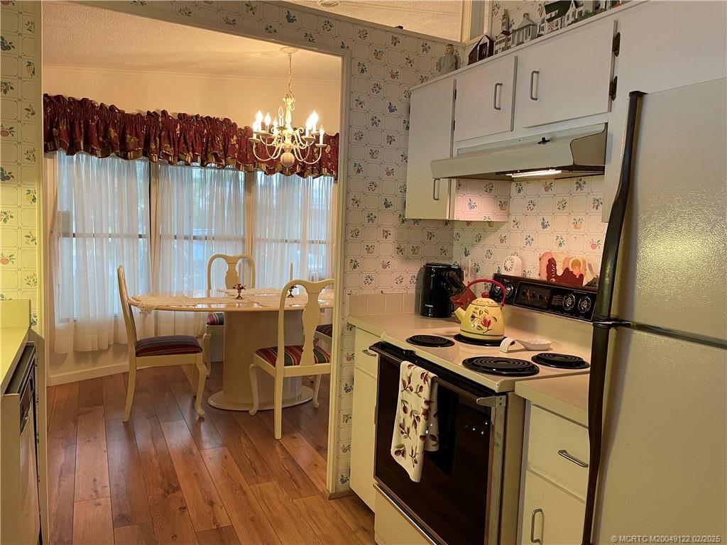 14663 Southwest Rake Drive Indiantown, FL 34956 - Photo 13 of 36 a kitchen with stainless steel appliances a stove a sink a chimney a dining table and chairs