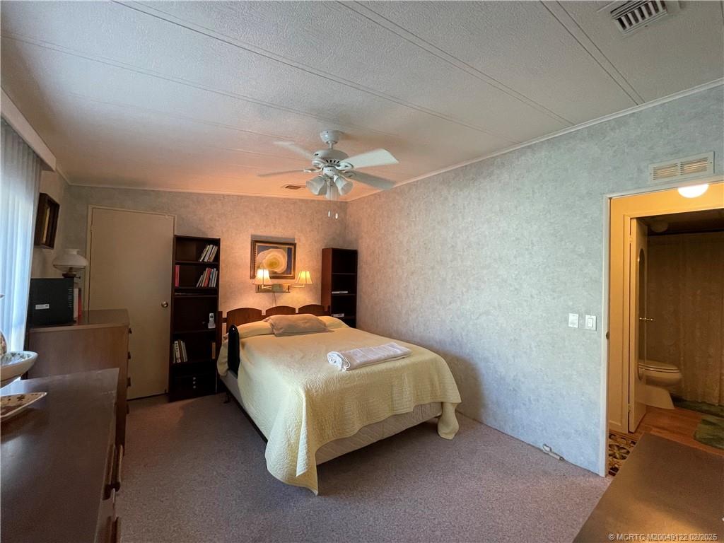 14663 Southwest Rake Drive Indiantown, FL 34956 - Photo 22 of 36 a bedroom with a bed and a chandelier