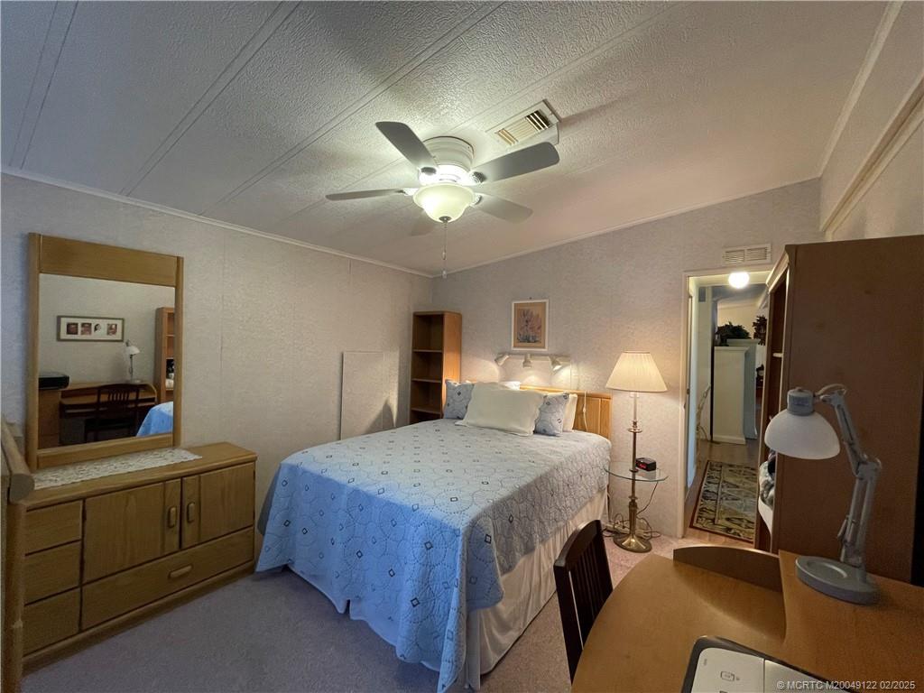 14663 Southwest Rake Drive Indiantown, FL 34956 - Photo 27 of 36 a bedroom with a bed and a chandelier