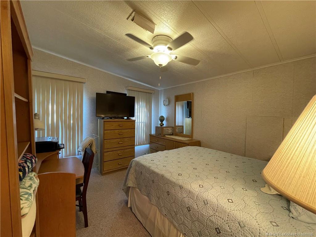 14663 Southwest Rake Drive Indiantown, FL 34956 - Photo 29 of 36 a bedroom with a bed and furniture with a flat tv screen