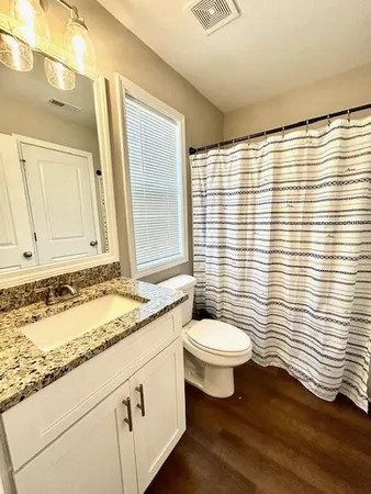 a bathroom with a granite countertop sink toilet a mirror and a shower