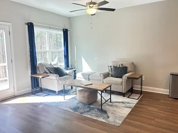 a living room with couches a coffee table and a dresser with wooden floor
