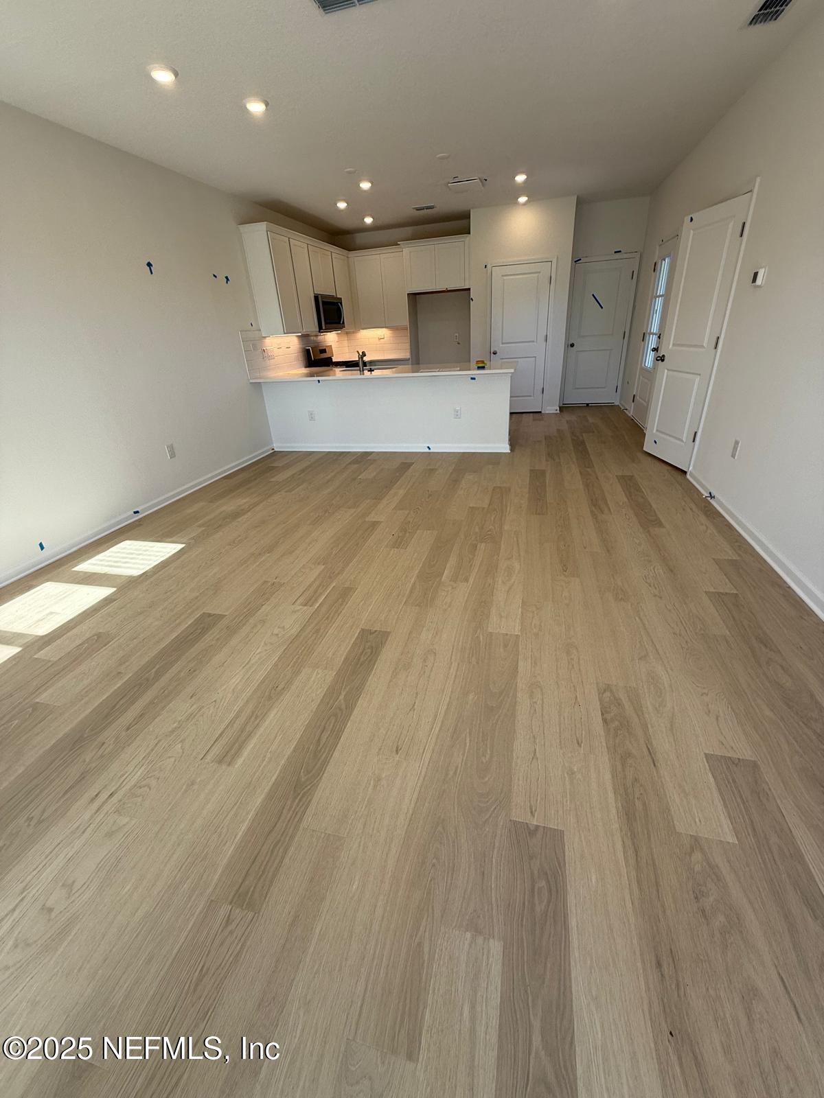 173 Wood Breeze Way St. Augustine, FL 32092 - Photo 29 of 36 a view of a kitchen with kitchen island a sink wooden floor and a counter top space