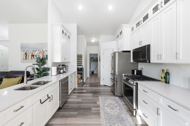 1816 River Bottom Road Springville, UT 84663 - Photo 3 of 37 Bright kitchen featuring white shaker cabinetry, stainless steel appliances, a double basin sink, light countertops, and wood-finish flooring
