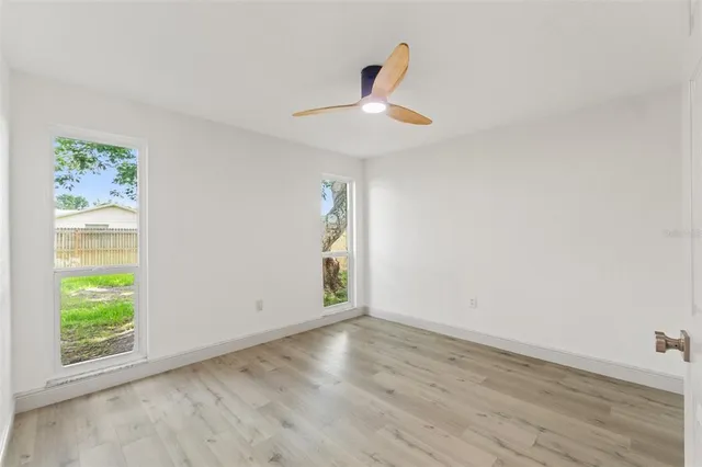 a view of empty room with wooden floor and fan