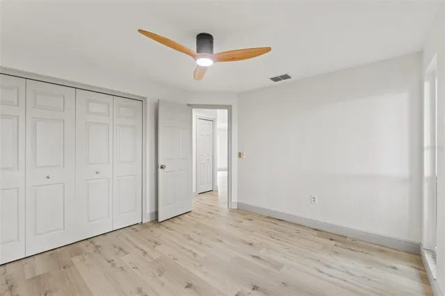 an empty room with wooden floor cabinet and windows