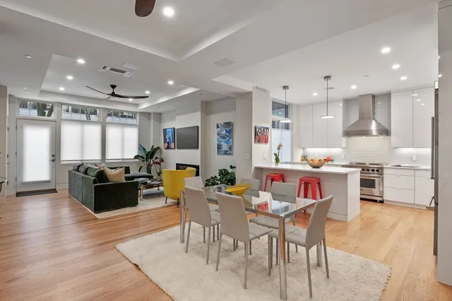 a kitchen with stainless steel appliances kitchen island granite countertop a dining table chairs and white cabinets