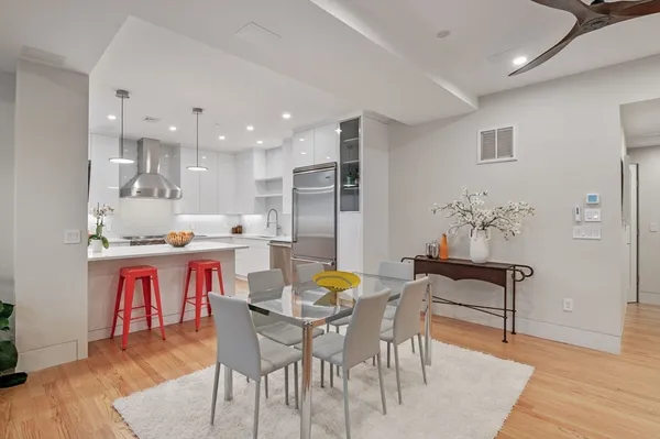 a dining area with stainless steel appliances kitchen island granite countertop a dining table chairs and a refrigerator