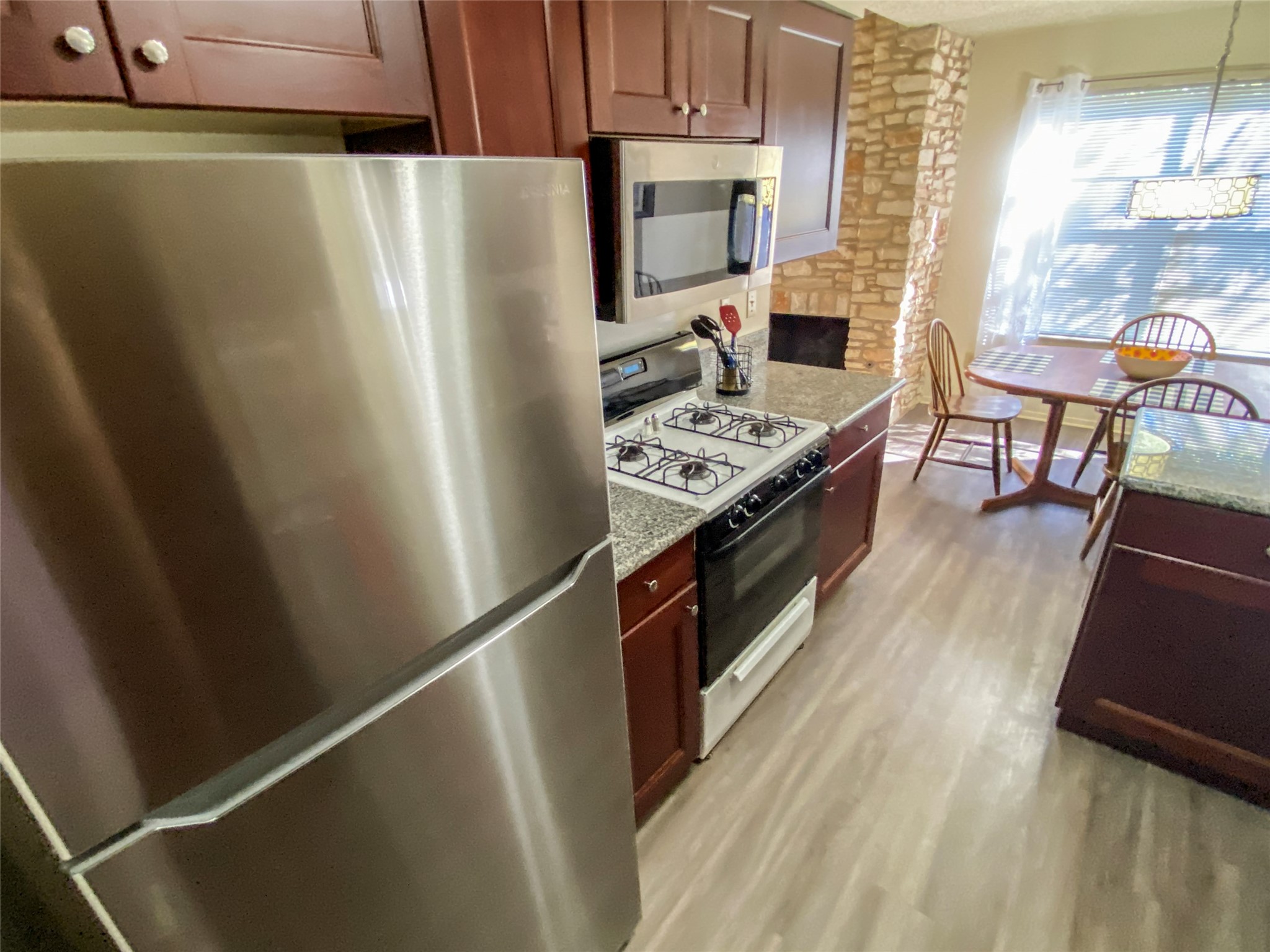 12905 Pegasus Street Austin, TX 78727 - Photo 14 of 32 a kitchen with stainless steel appliances a refrigerator a stove a sink dishwasher and a dining table with wooden floor
