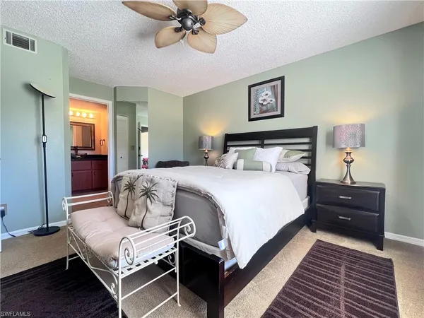 a bedroom with bed couches and a flat tv screen on dresser