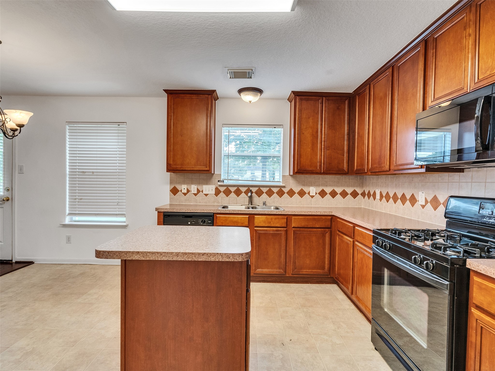3307 Manor Tree Lane Houston, TX 77068 - Photo 13 of 44 This kitchen features warm wooden cabinetry, a central island, and a gas stove. There's ample counter space, modern appliances, and natural light from a window by the sink. The tile backsplash adds a decorative touch.