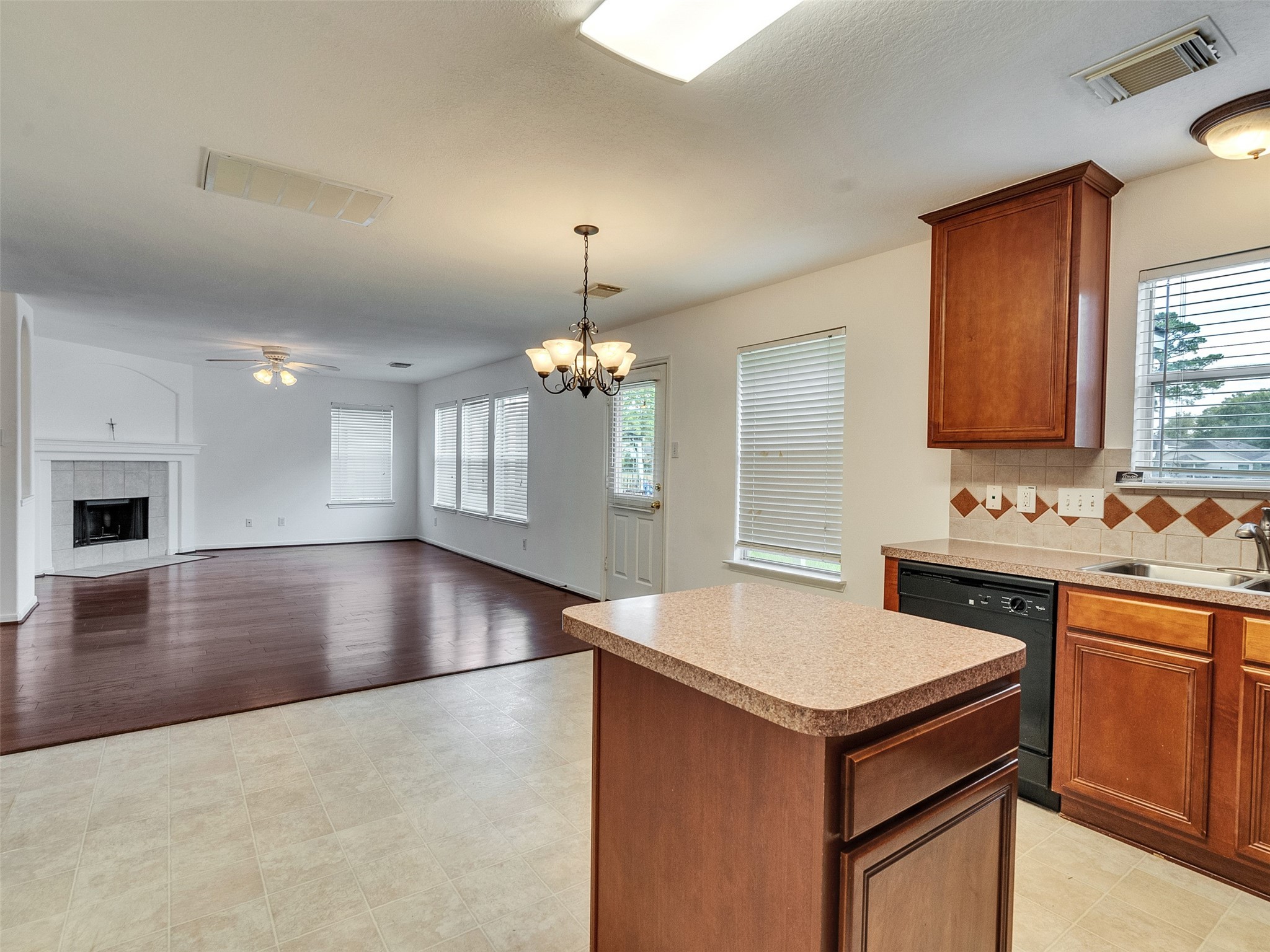 3307 Manor Tree Lane Houston, TX 77068 - Photo 14 of 44 This photo shows an open-concept living area with hardwood floors and a cozy fireplace. The adjacent kitchen features a central island, modern appliances, and ample natural light from multiple windows.