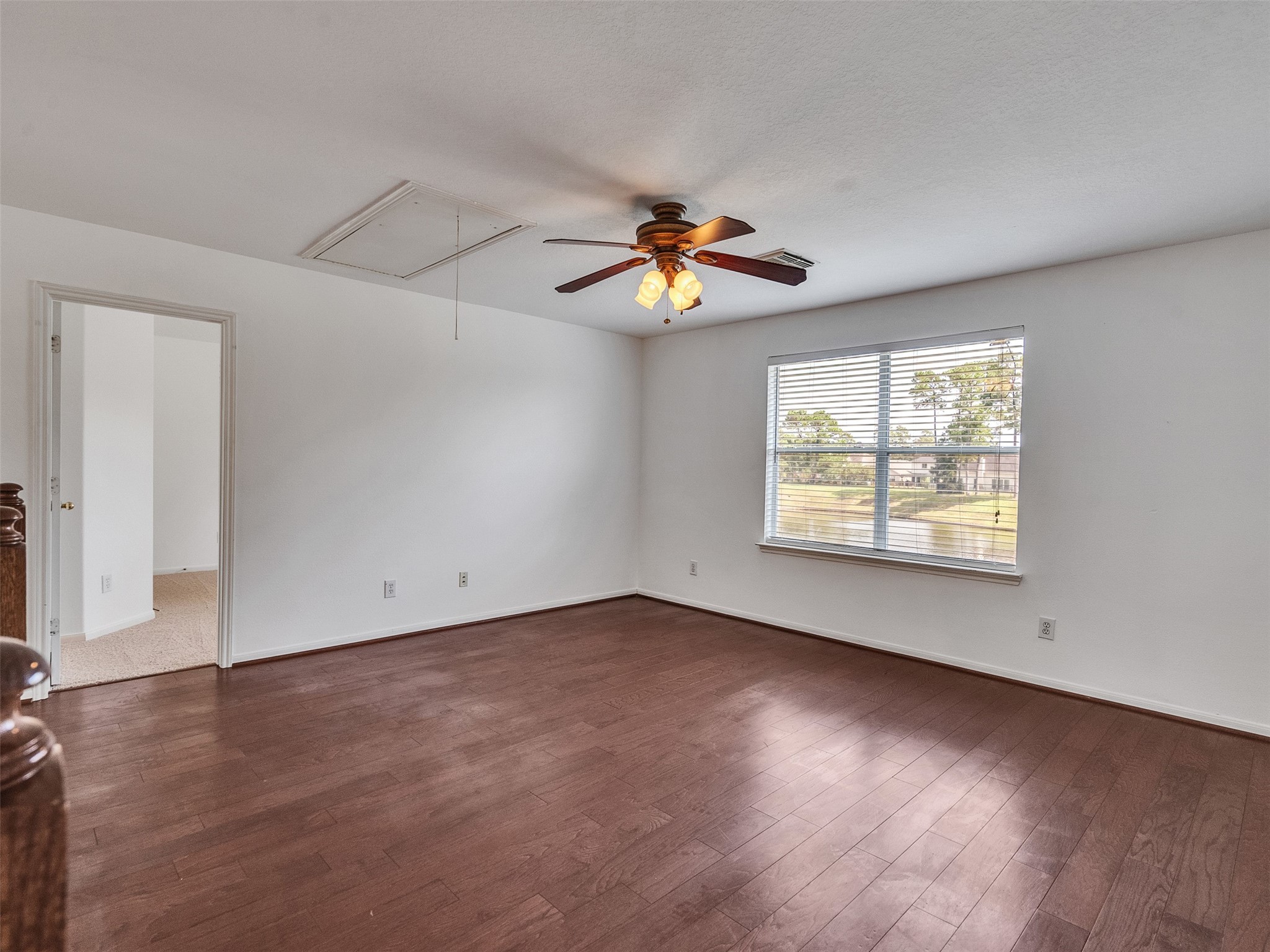 3307 Manor Tree Lane Houston, TX 77068 - Photo 19 of 44 This game room features hardwood floors, a ceiling fan with lights, and a large window offering natural light and views of greenery. It connects to another room through a doorway.