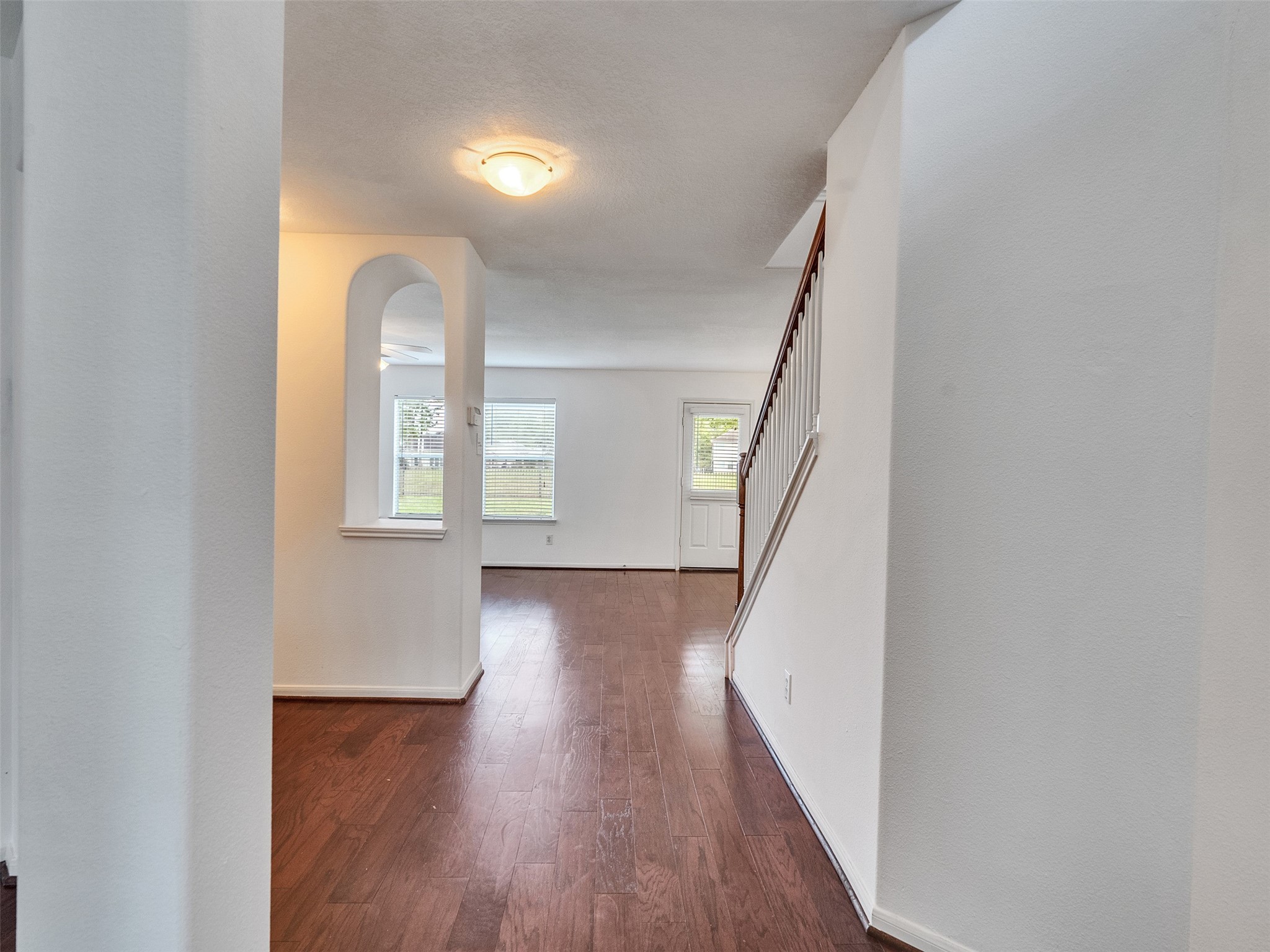 3307 Manor Tree Lane Houston, TX 77068 - Photo 2 of 44 This photo showcases a bright and open interior space with hardwood floors and white walls. There's a staircase leading to an upper level, and a well-lit area with windows near the entrance, offering a welcoming and spacious feel.