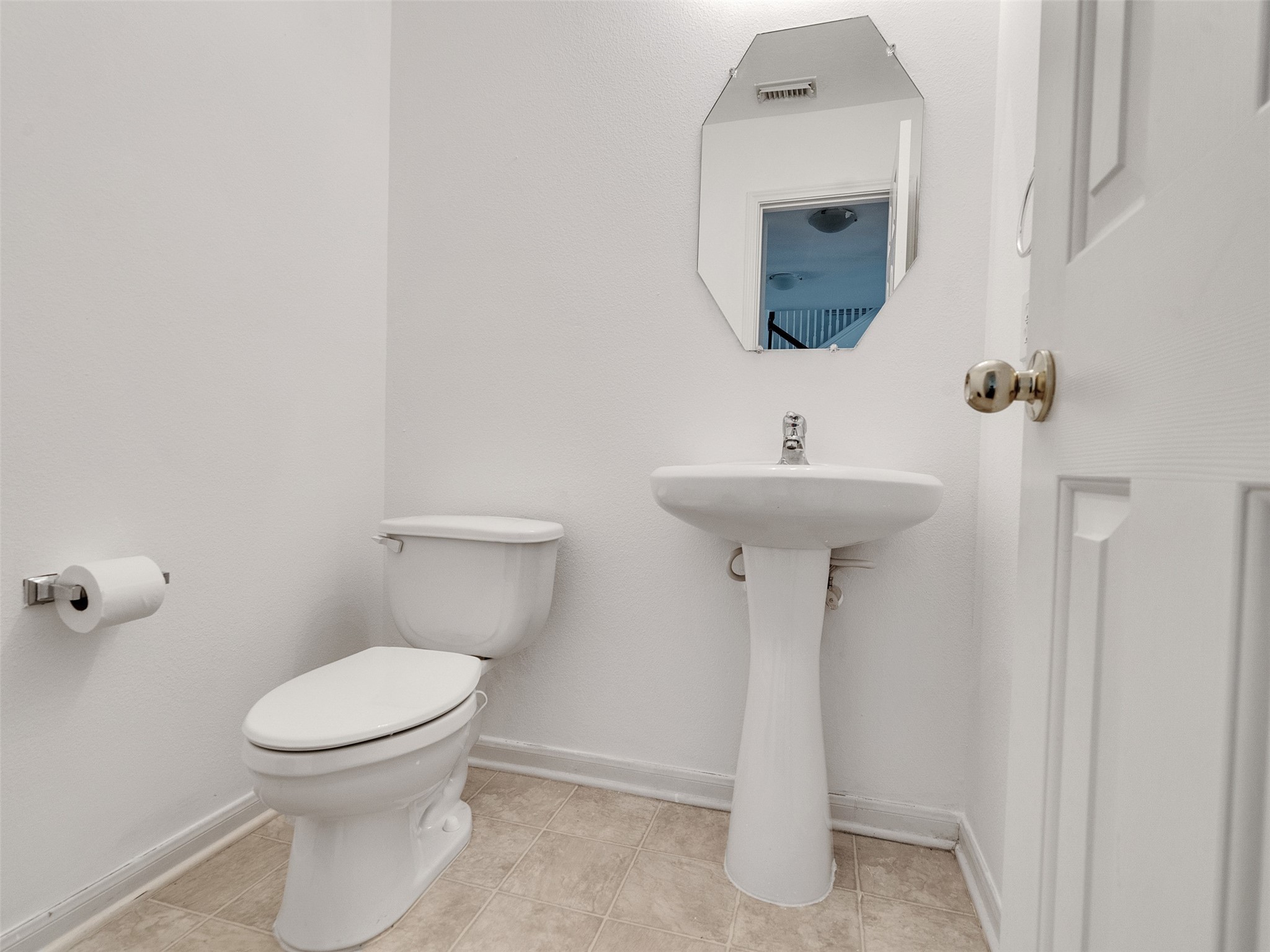 3307 Manor Tree Lane Houston, TX 77068 - Photo 32 of 44 Compact half-bathroom with a pedestal sink and toilet. Features a small, angular mirror and neutral tile flooring. Simple and functional design.