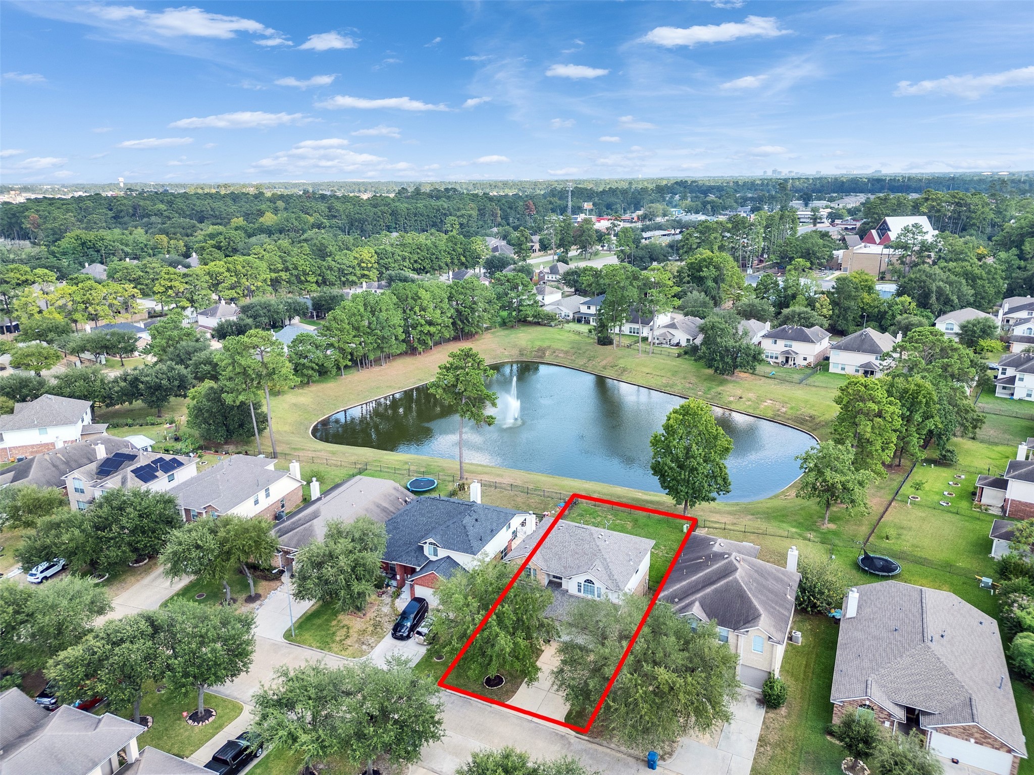 3307 Manor Tree Lane Houston, TX 77068 - Photo 33 of 44 This aerial photo showcases a charming home outlined in red, situated in a tranquil neighborhood. The property is near a scenic pond with a fountain, surrounded by lush greenery, offering a peaceful setting. Perfect for buyers seeking a serene environment.