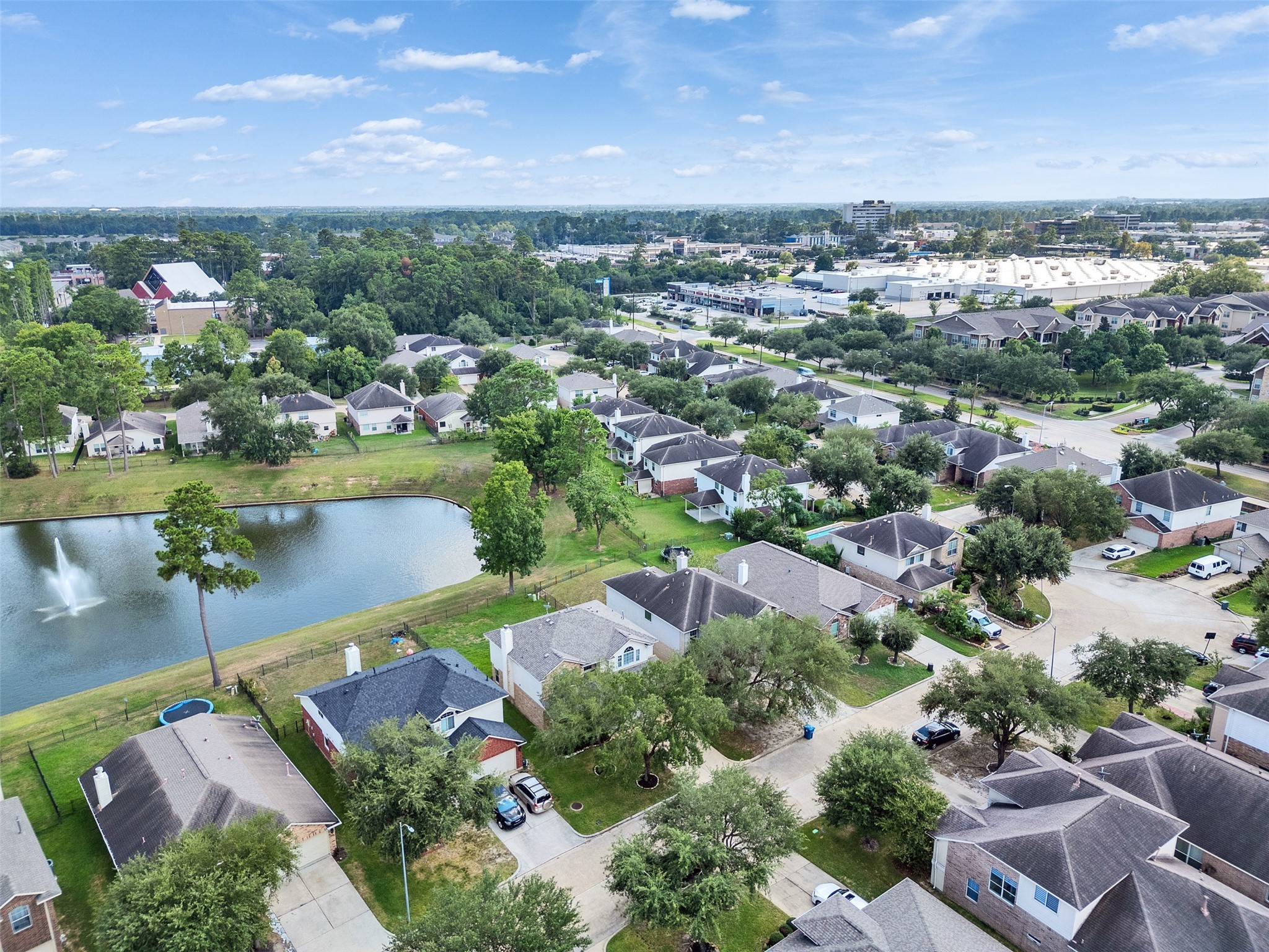 3307 Manor Tree Lane Houston, TX 77068 - Photo 34 of 44 This aerial photo showcases a peaceful suburban neighborhood with a charming pond featuring a fountain. The area is lined with well-maintained homes, surrounded by lush greenery and trees, offering a tranquil and picturesque setting.