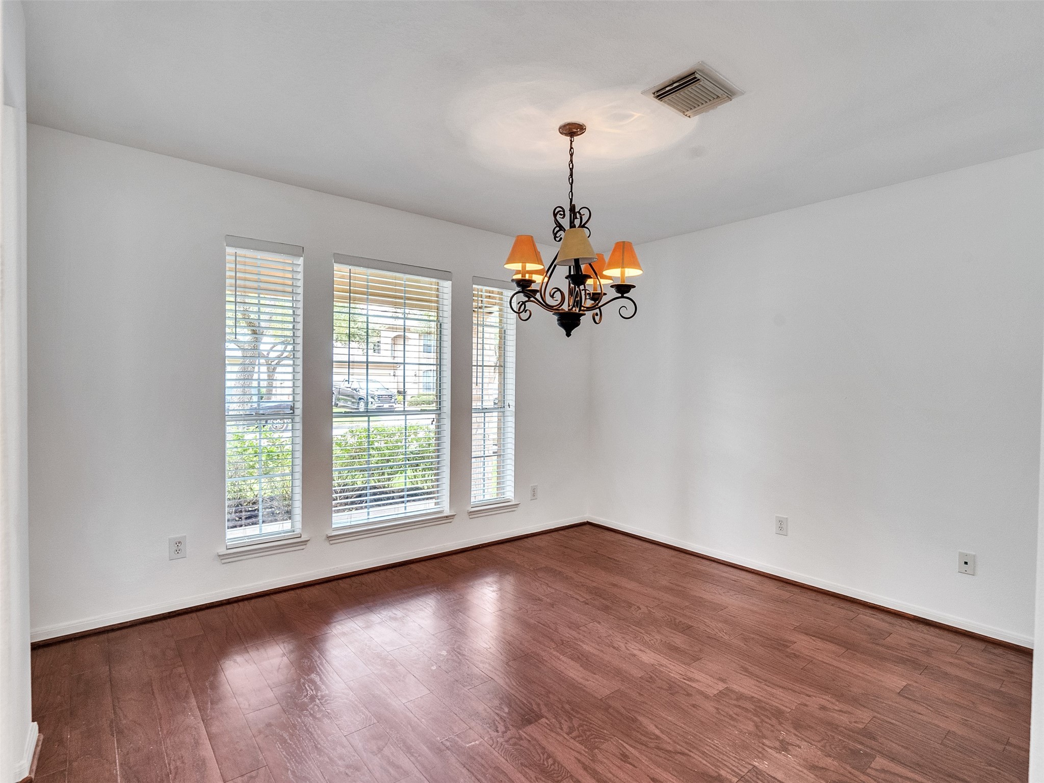 3307 Manor Tree Lane Houston, TX 77068 - Photo 4 of 44 This room features hardwood floors, a classic chandelier, and large windows with blinds, offering plenty of natural light. Perfect for a dining or living area.