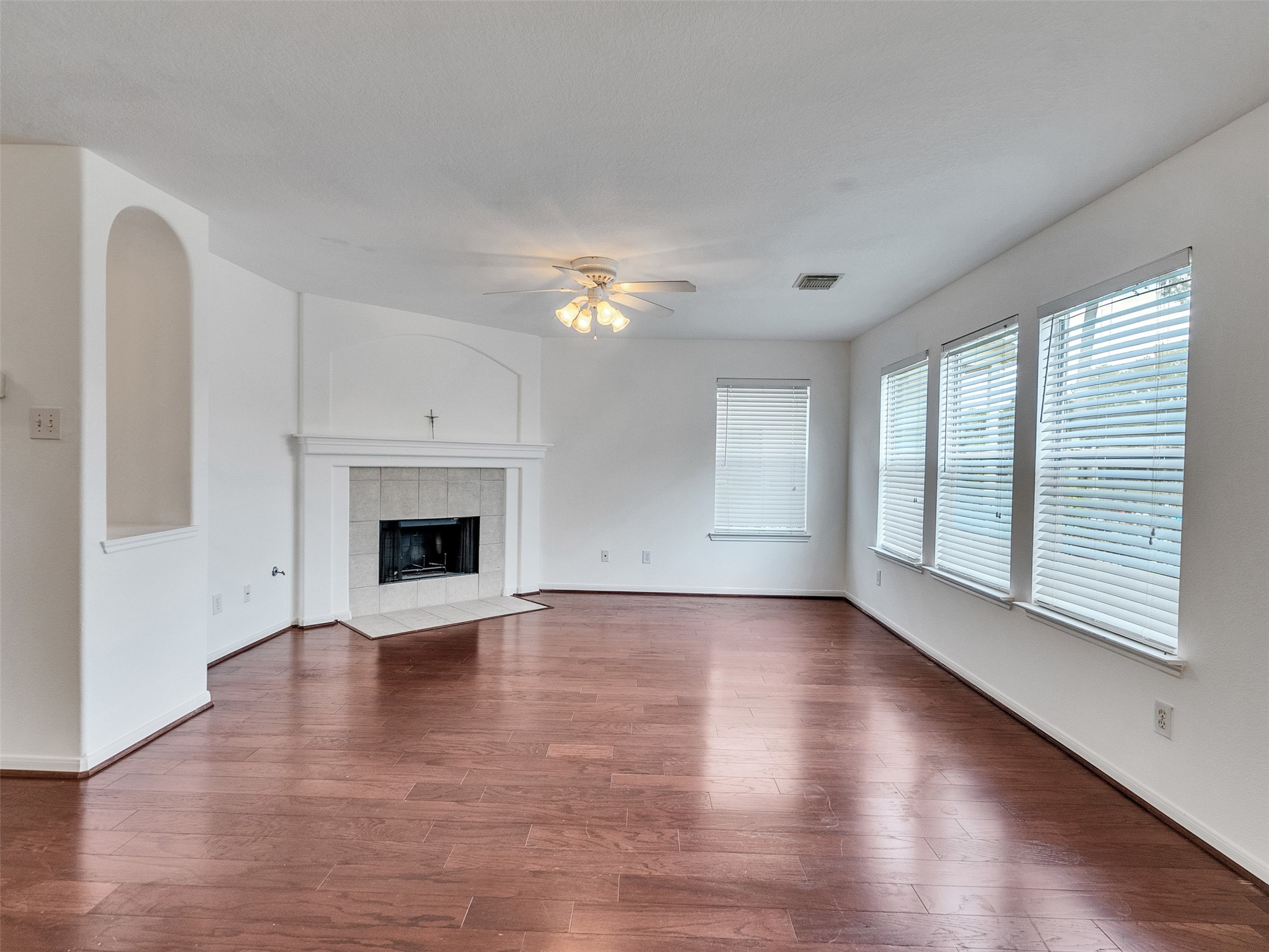 3307 Manor Tree Lane Houston, TX 77068 - Photo 7 of 44 This spacious living room features rich hardwood floors, a cozy fireplace, and ample natural light from multiple windows with blinds. The ceiling fan adds comfort, while the neutral walls create a versatile space for any decor style.